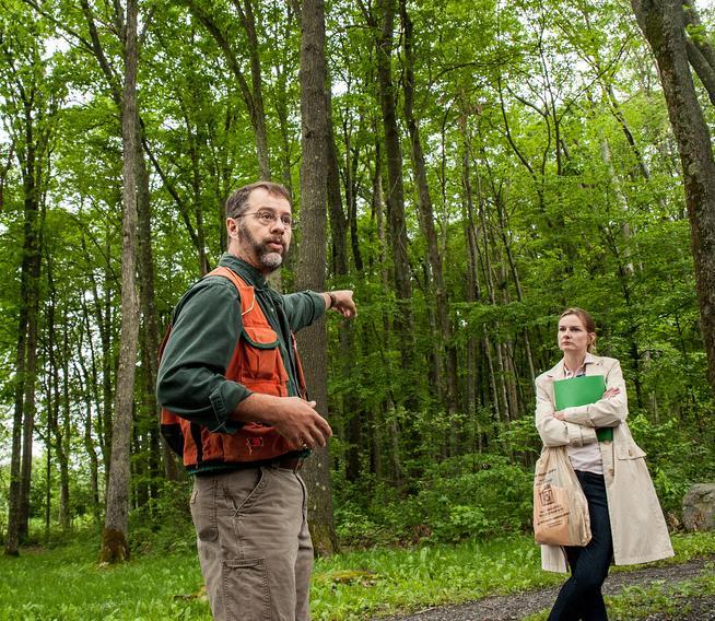 Man standing and pointing to the forest, women watches