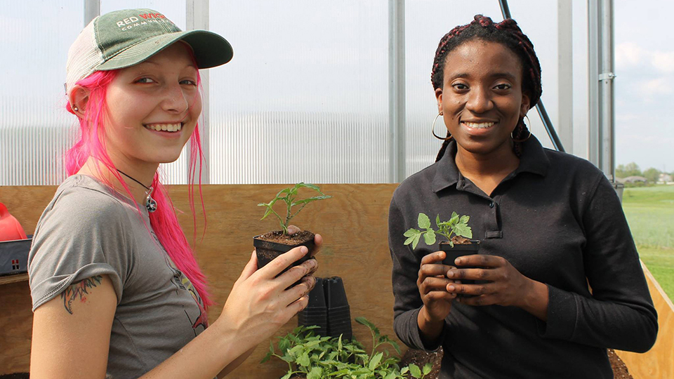 Two female students holding up plants