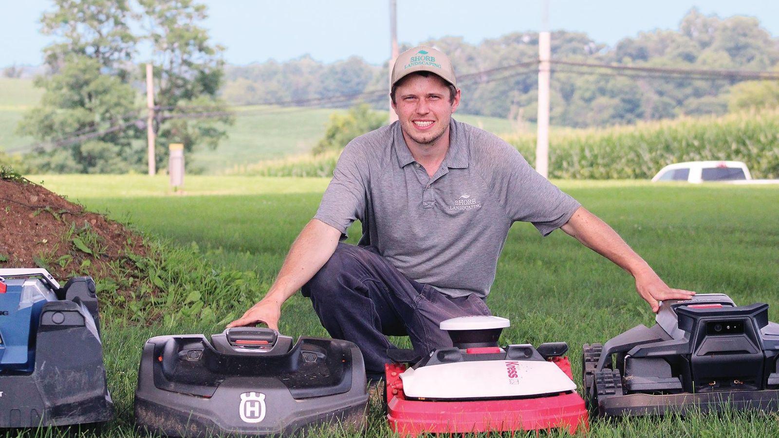 Brandon Writt kneeling over autonomous mowers