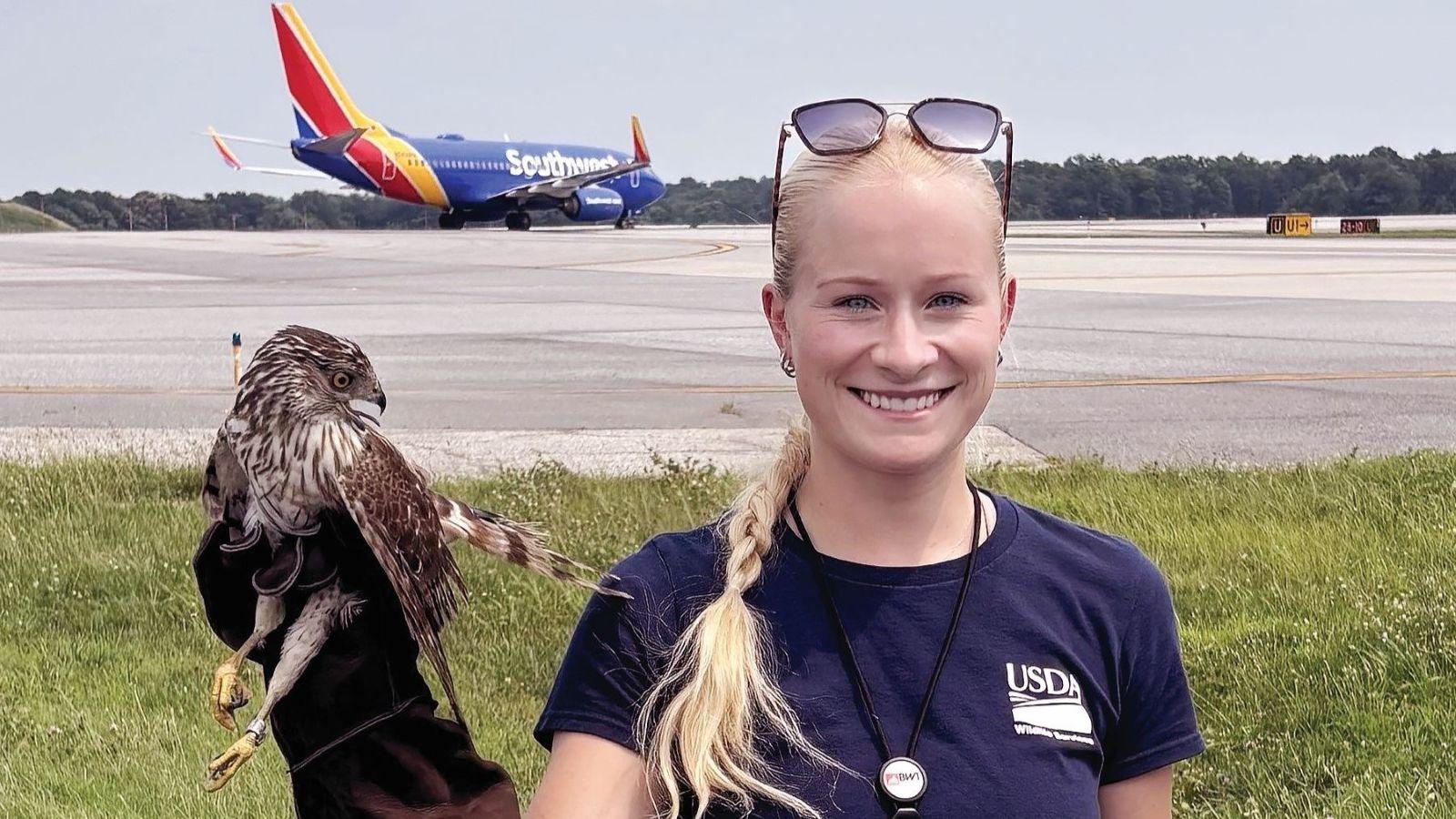 Alum holding up a hawk in front of an airport