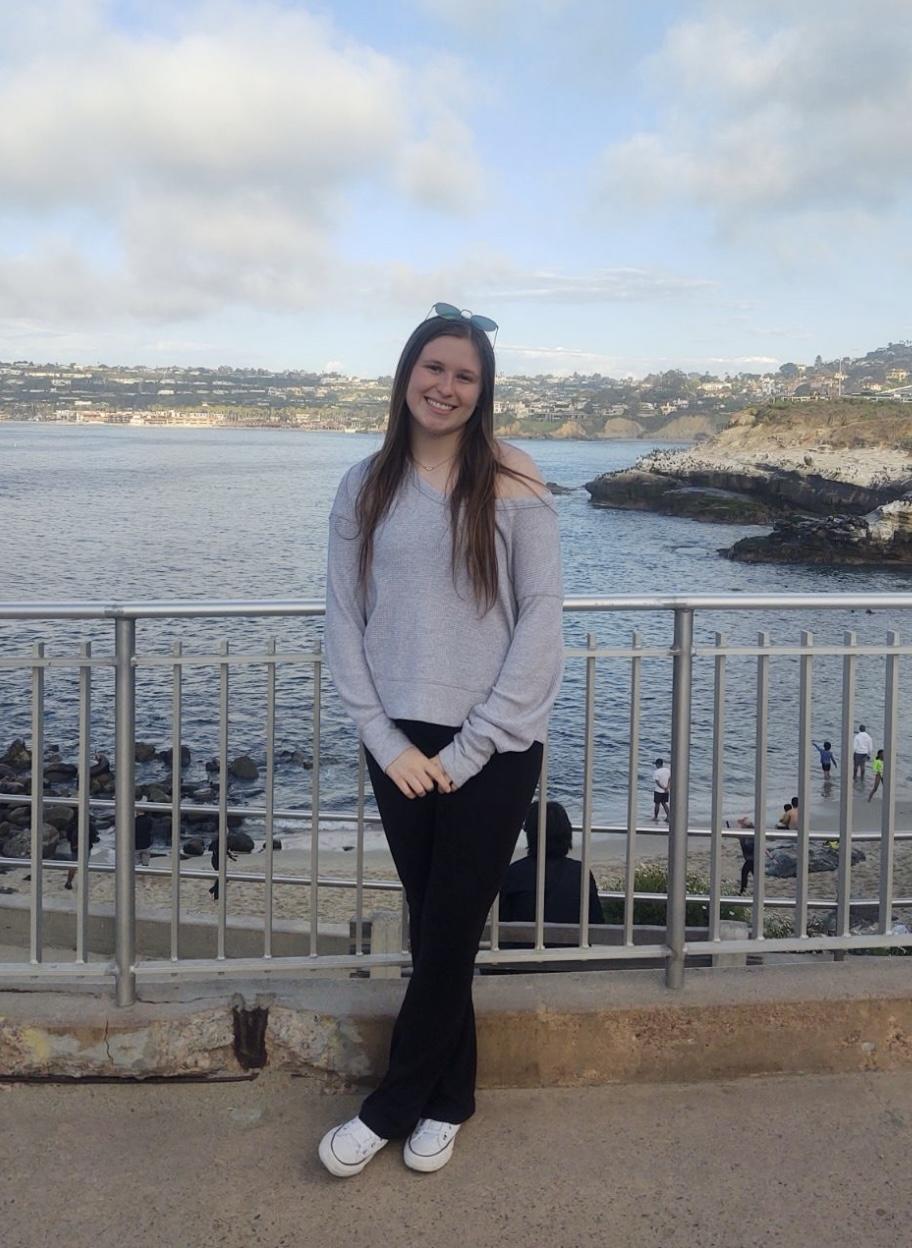 Smiling student against the backdrop of a rocky shoreline.