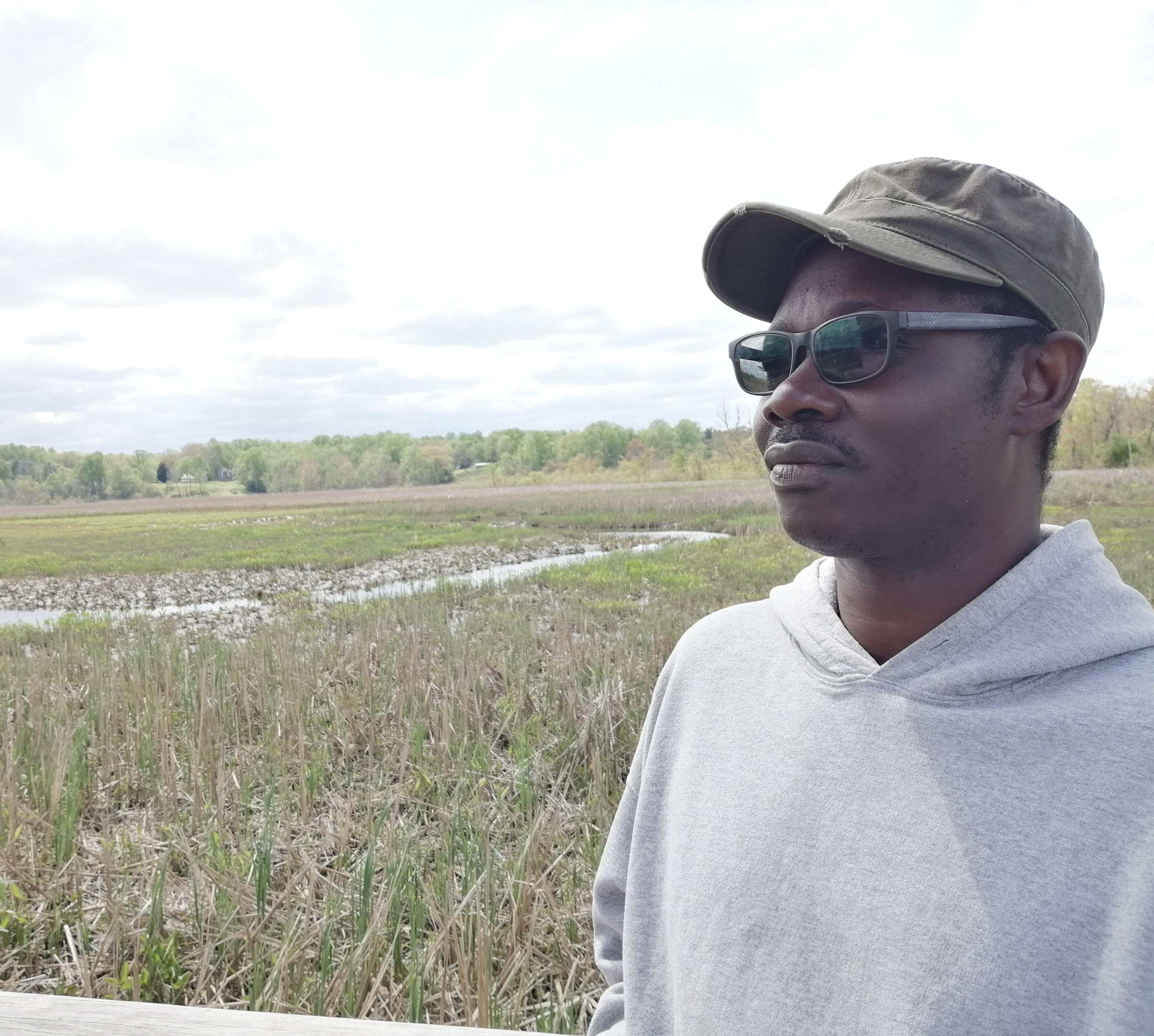 Farmer, Kwesi Asante, looking out over a green field