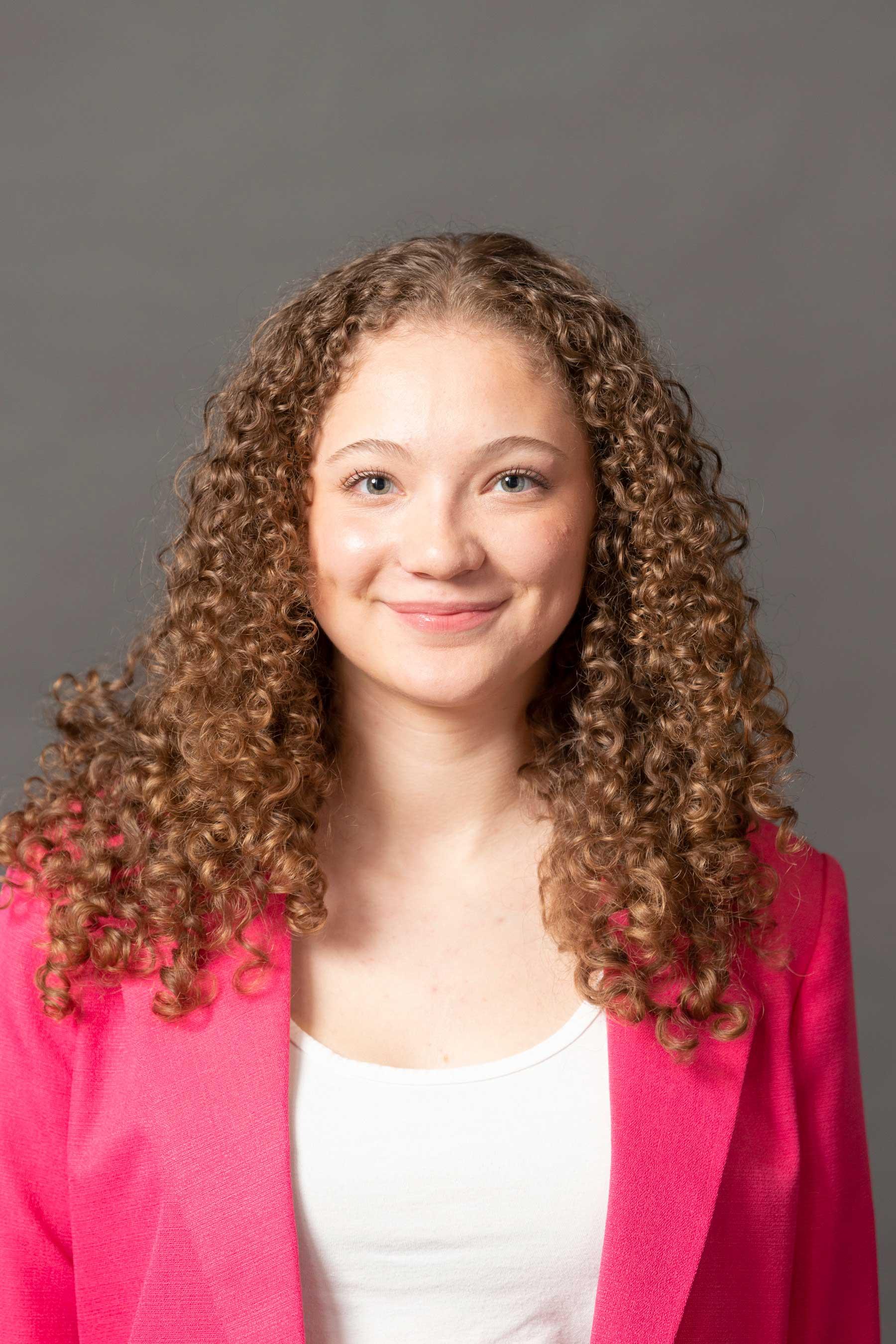 Beautiful curls abound on this professionally dressed, smiling student wearing fuschia.