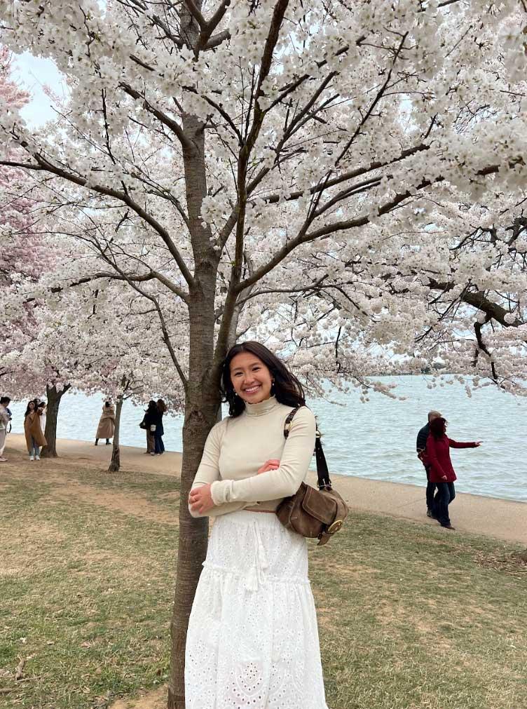 Happy student leaning on flowering Cherry Blossom