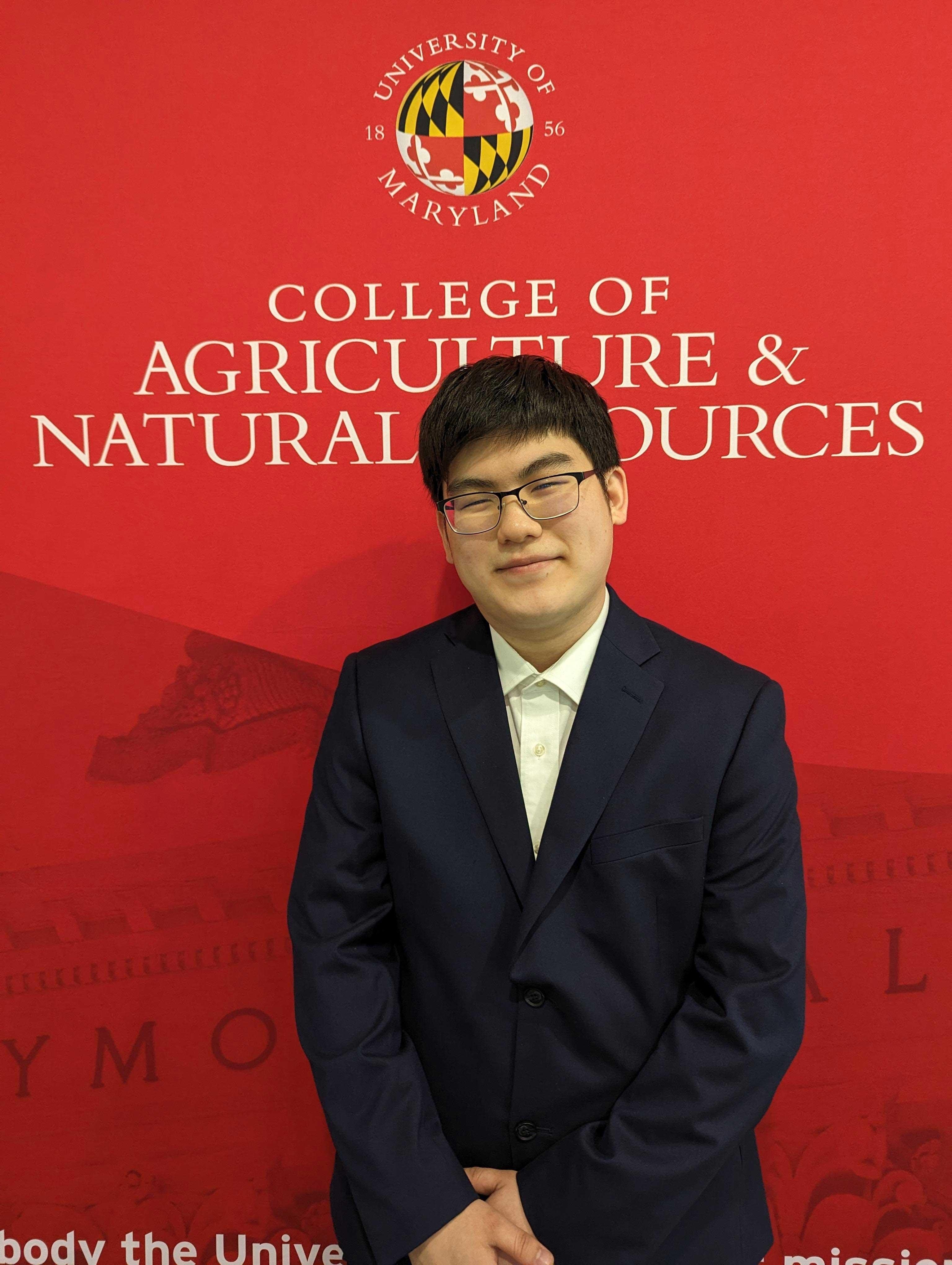 Proud student awardee standing in front of College of Agriculture and Natural Resources backdrop.