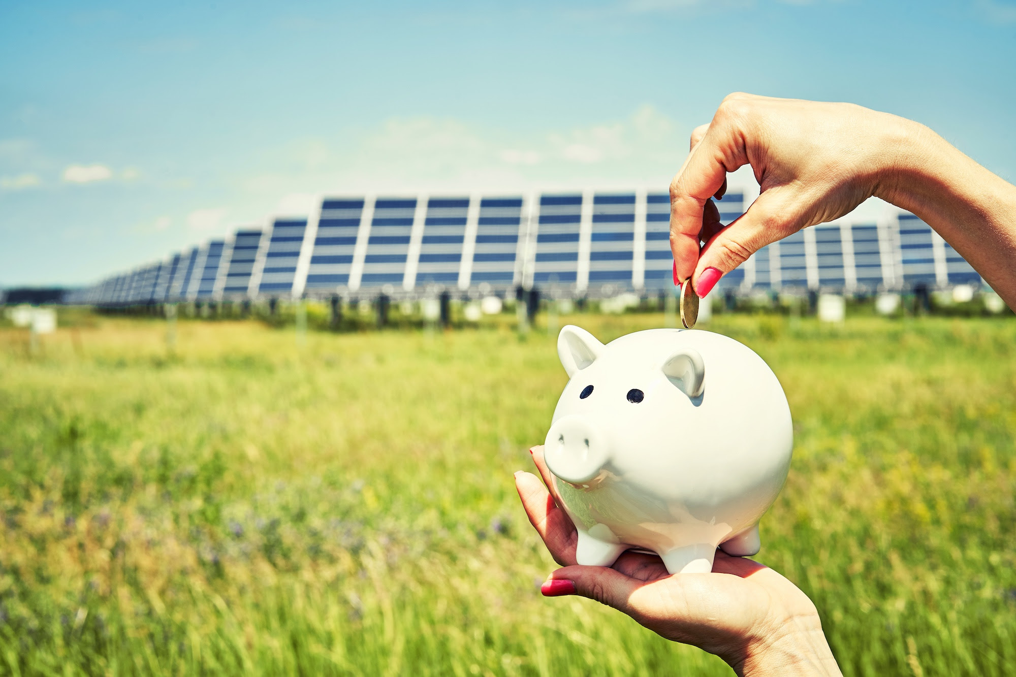 Image of piggy bank with solar panels in background by Sergei Domashenko