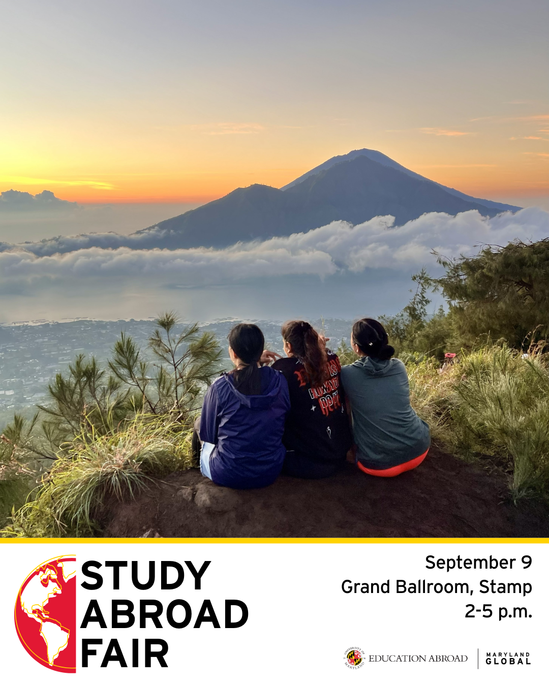 Students sitting overlooking a beautiful mountain and water scene