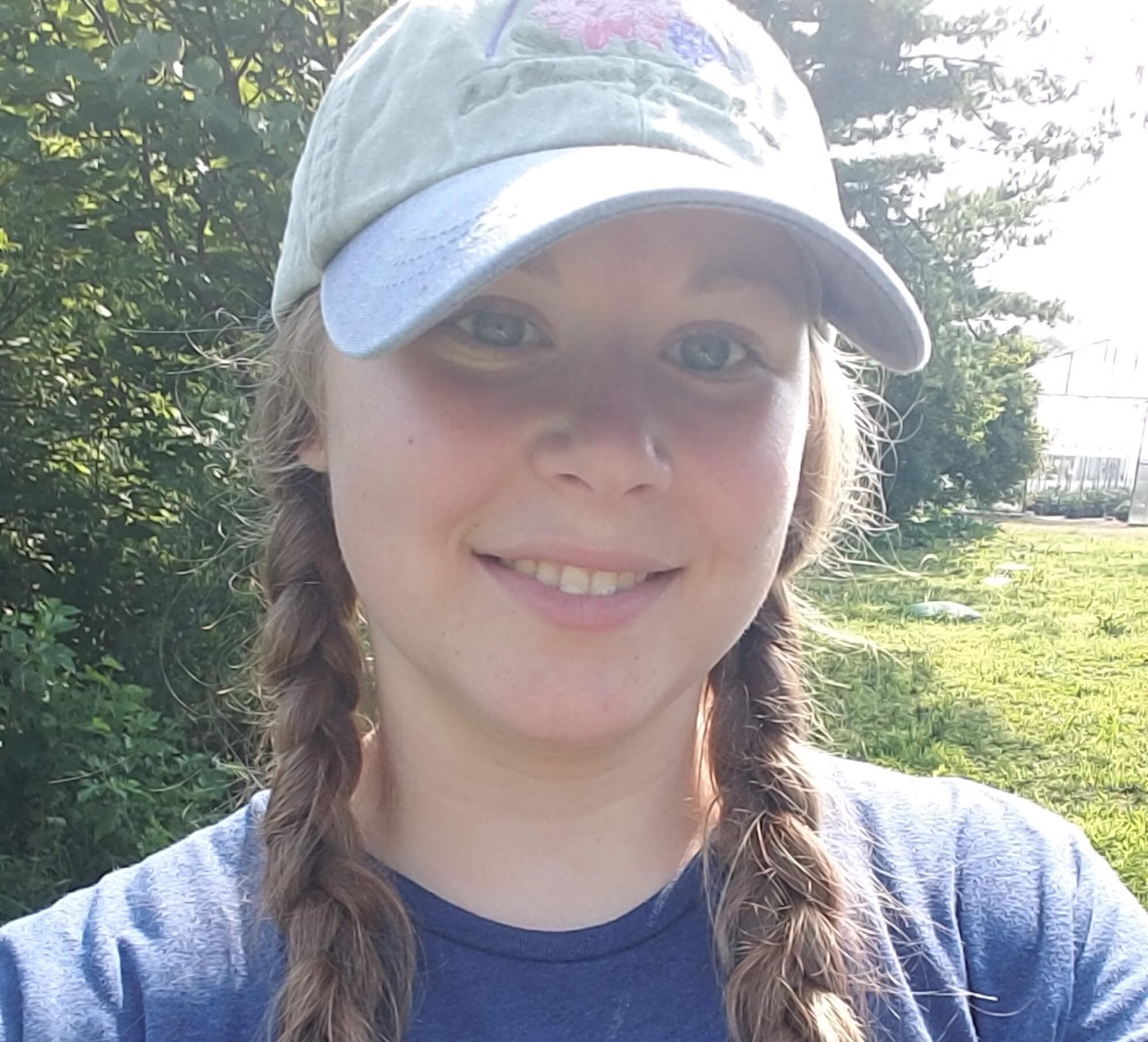 Selfie of alum Lydia Printz wearing a baseball hat and blue shirt