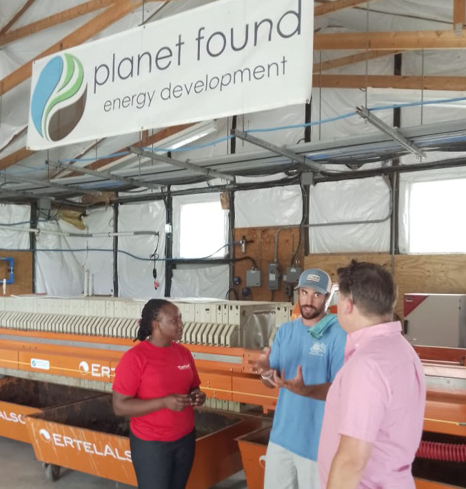 Grace Nalugwa (left) and Dave Tilley (right) interview Nick from Planet Found Energy, a poultry farm that hopes to feed electricity  generated from chicken litter to the national grid.
