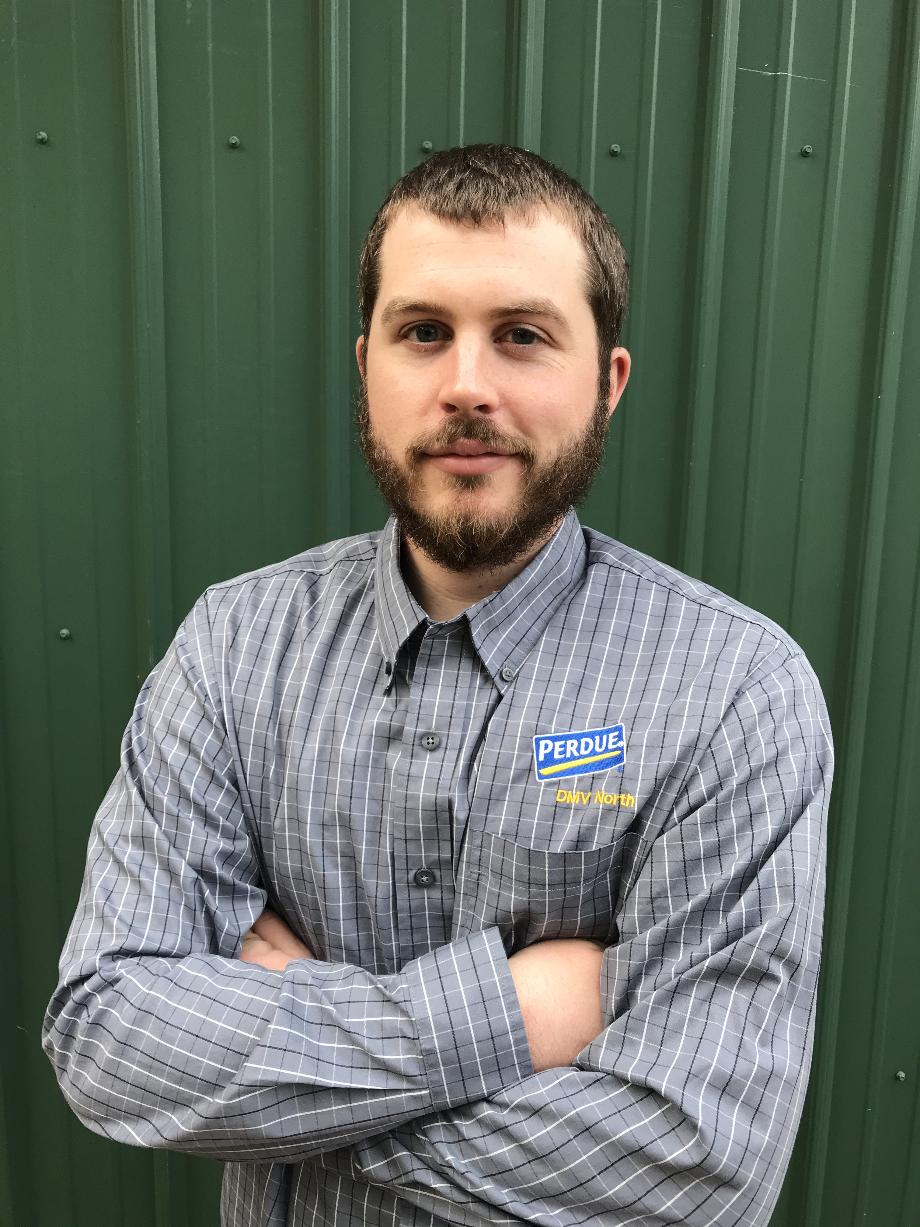 AGNR Alum Bret Bucci stands in front of green background in his company Perdue shirt