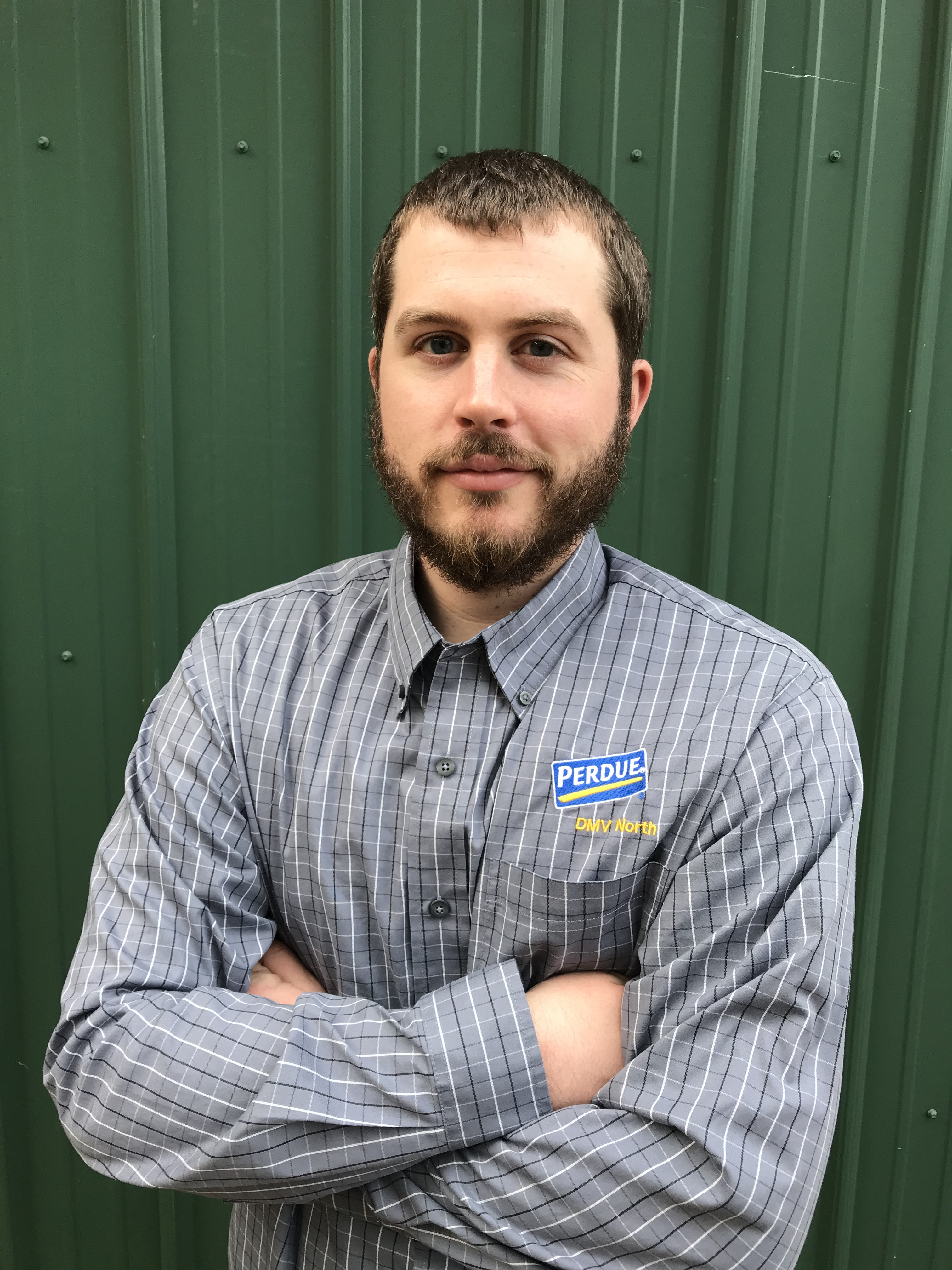 Headshot photo of alum Bret Bucci standing in front of a green background in his perdue employee shirt