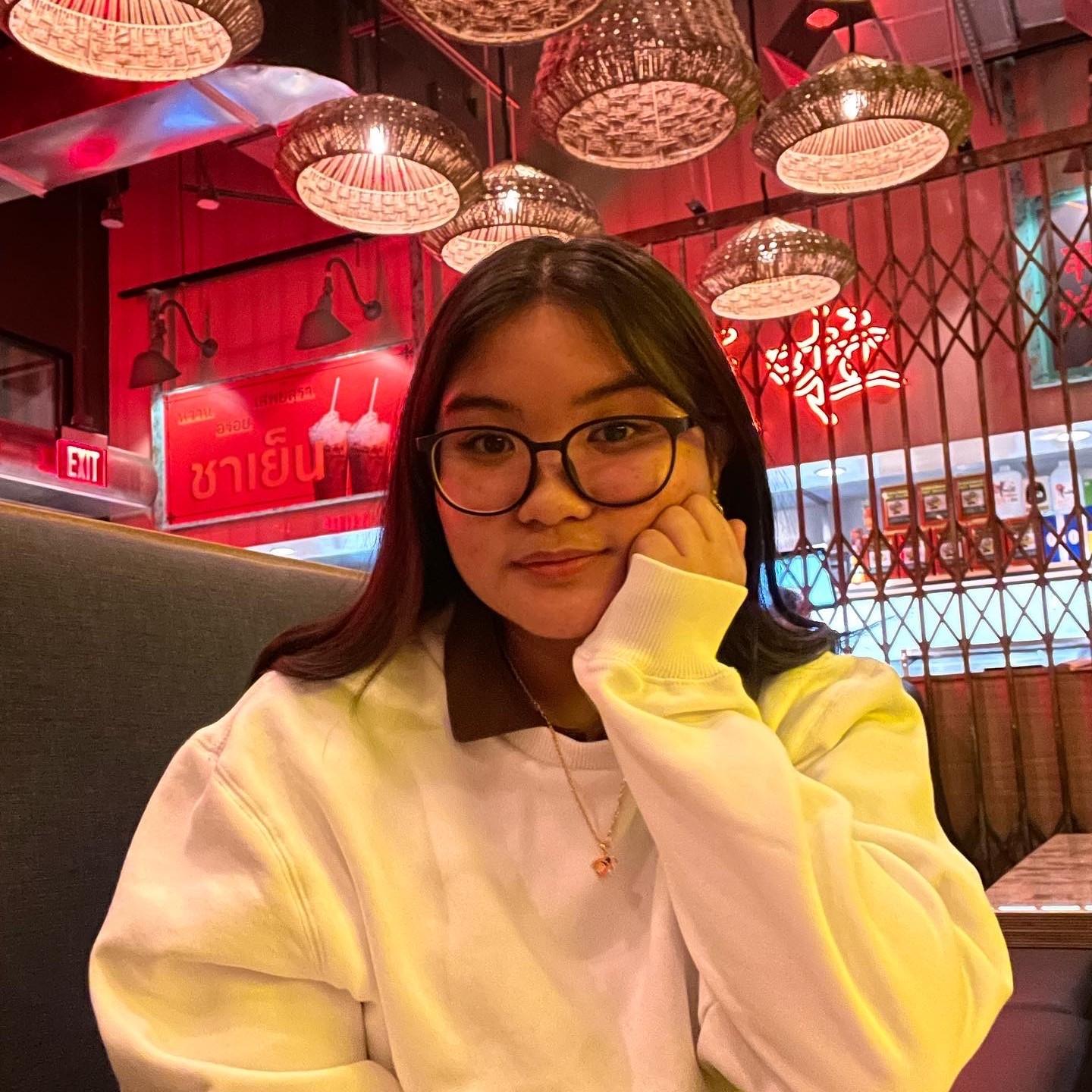 Grazelle is smiling in a white sweatshirt, eating at Hawkers Asian Street Food in Bethesda, MD