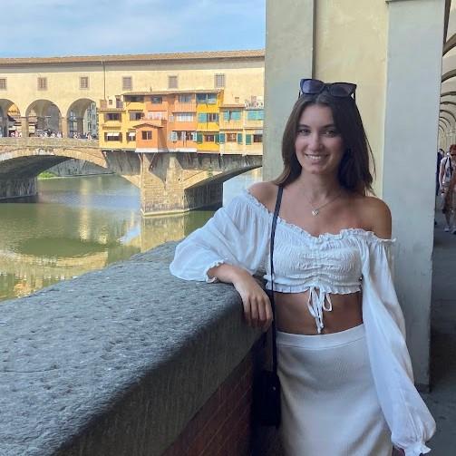 Maria is smiling, posing in front of the famous Ponte Vecchio in Florence, Italy