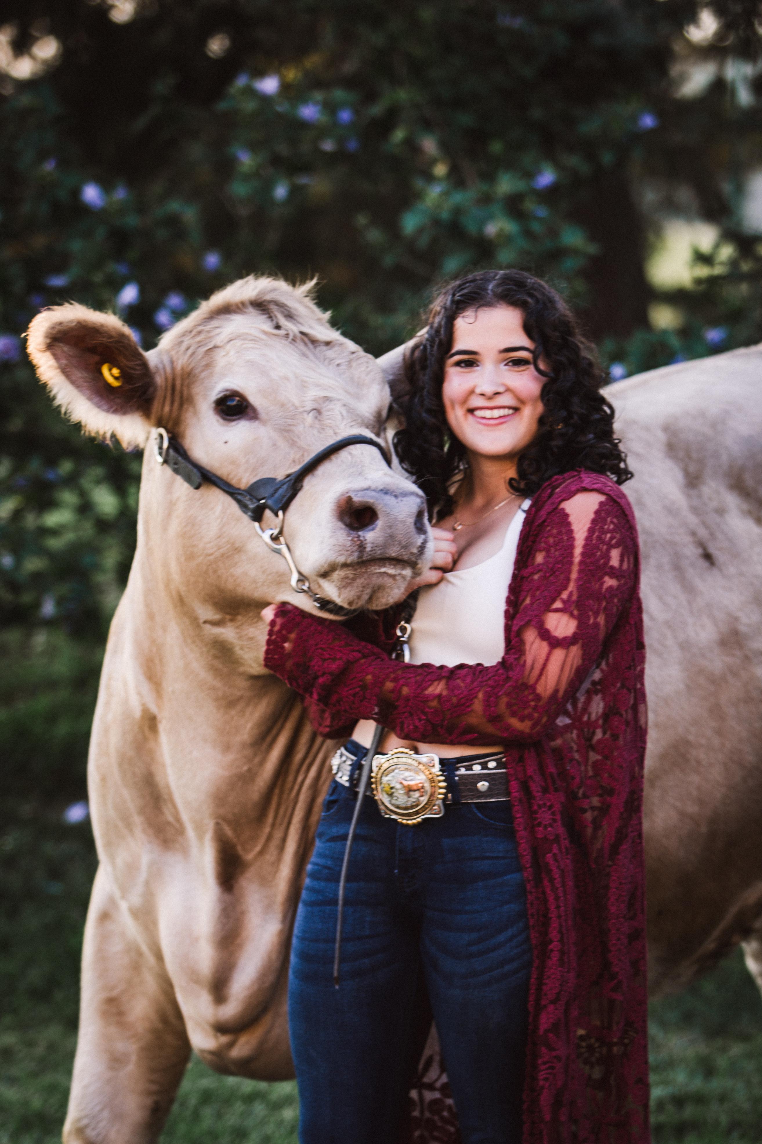 Raven Herron. A student happily posing with a very large, cross-breed, Charolais/Angus.