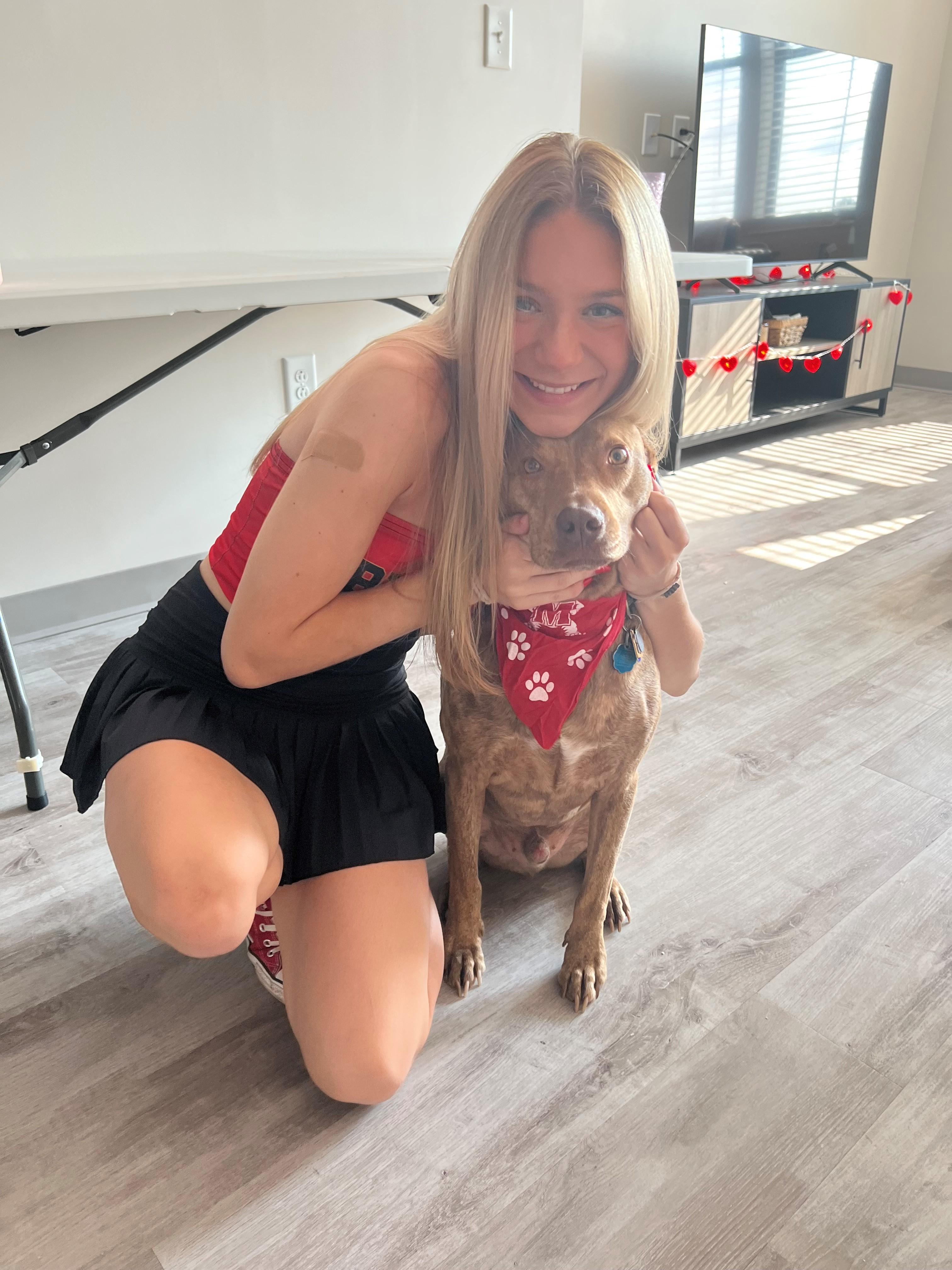 Cassidy Gitch. Happy student holding dog with red  bandana neckerchief.