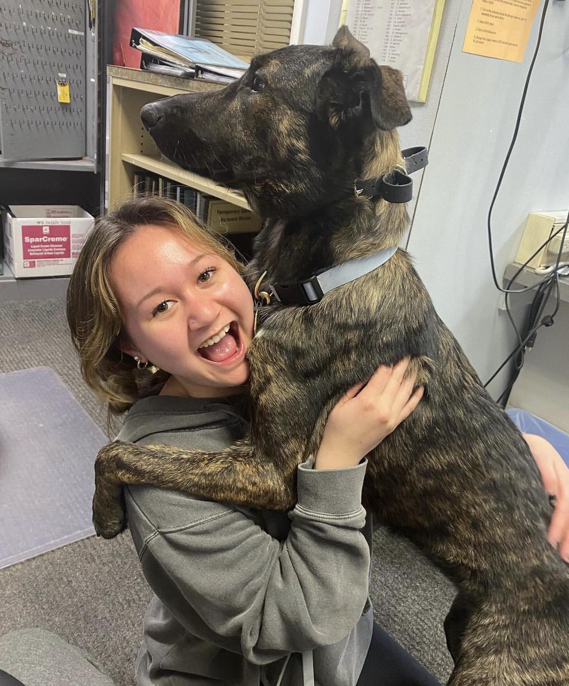 Kelly Whalen. Joyful student holding dog larger than she is.