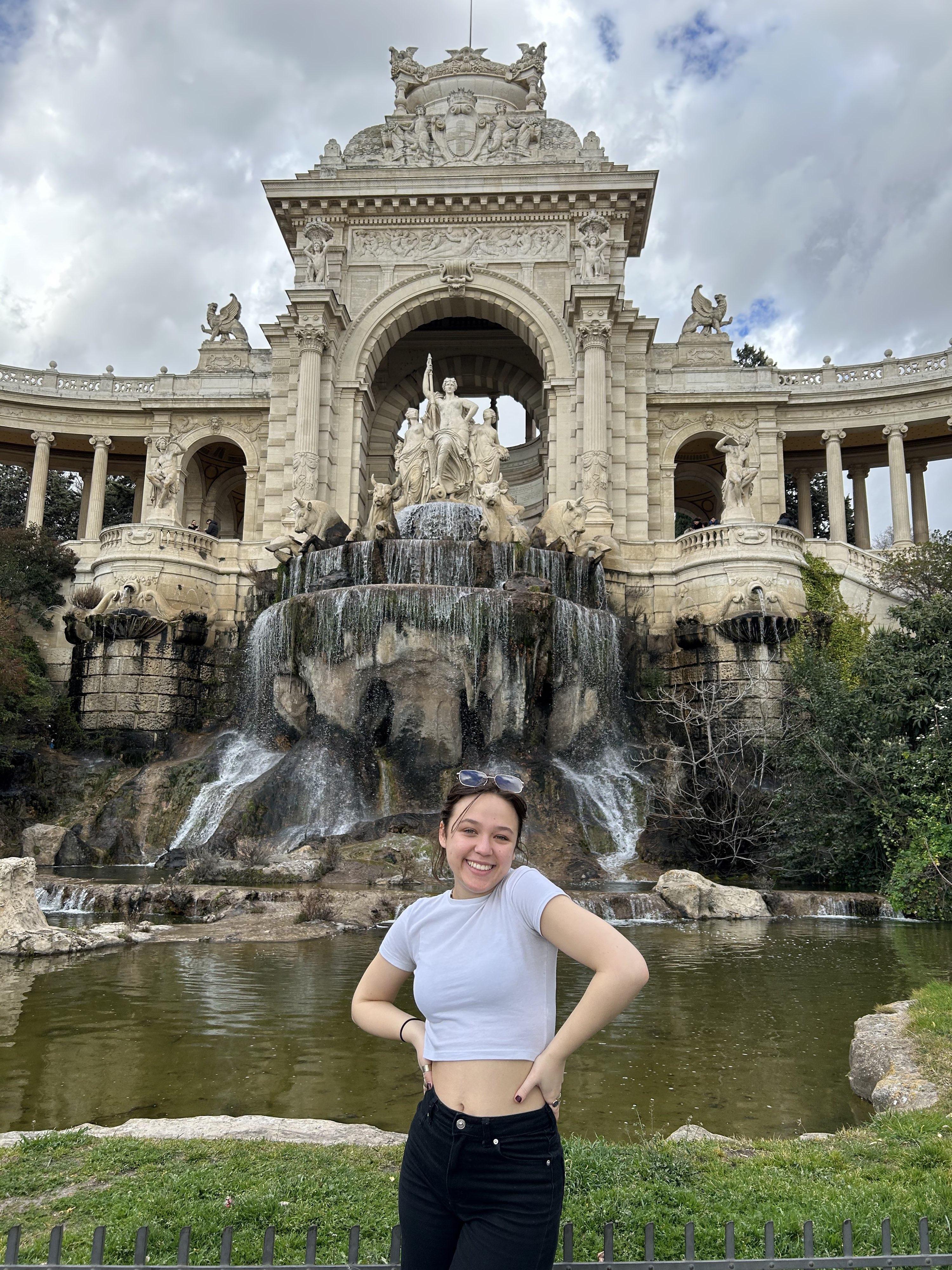 Kathleen Quinn.  Student on study abroad posing happily in front of Palais Longchamp.