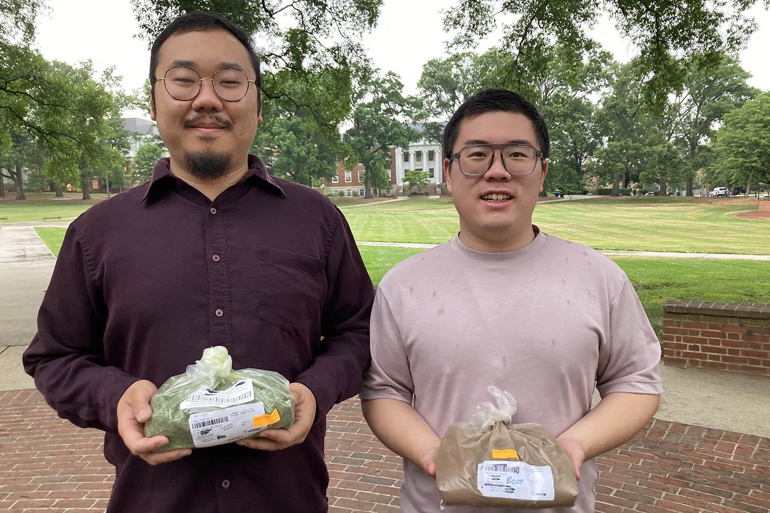 Ethan Young-Hyun Lee and Fangxiang Dong holding the herbs they are investigating for their antiviral properties.