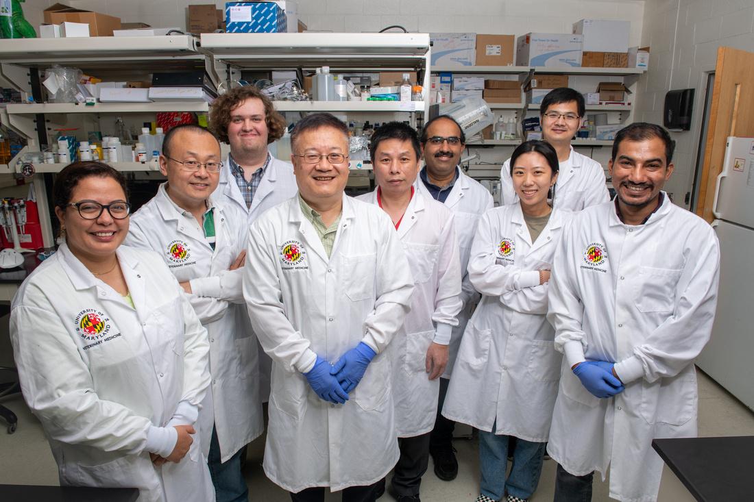 Man smiling in lab coat with team behind him