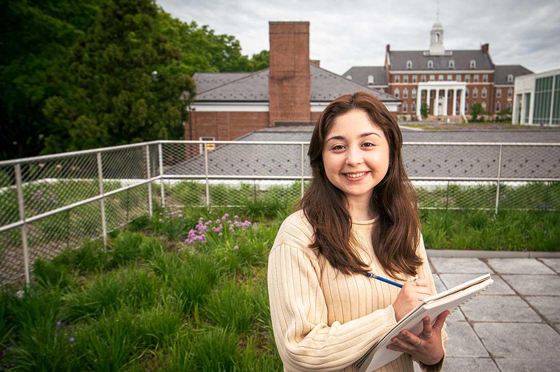 Student holding a sketch pad on top of a roof