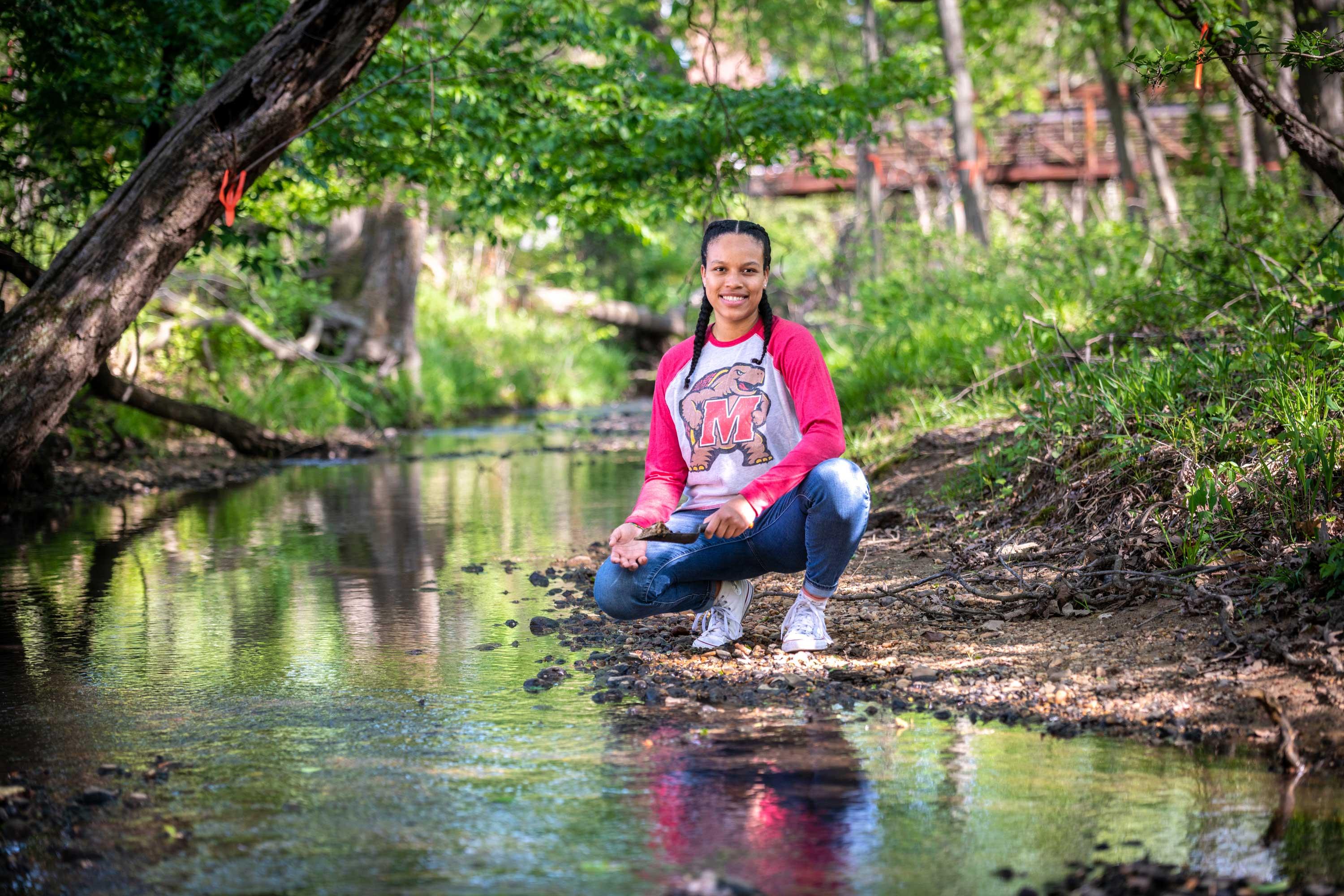 Student at a creek collecting soil samples