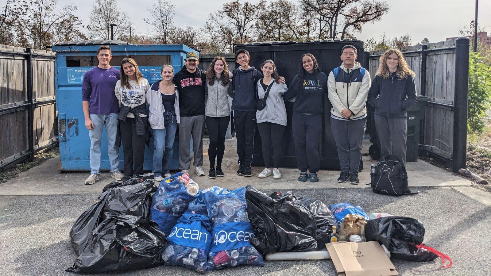 Students standing in front of trash bags 