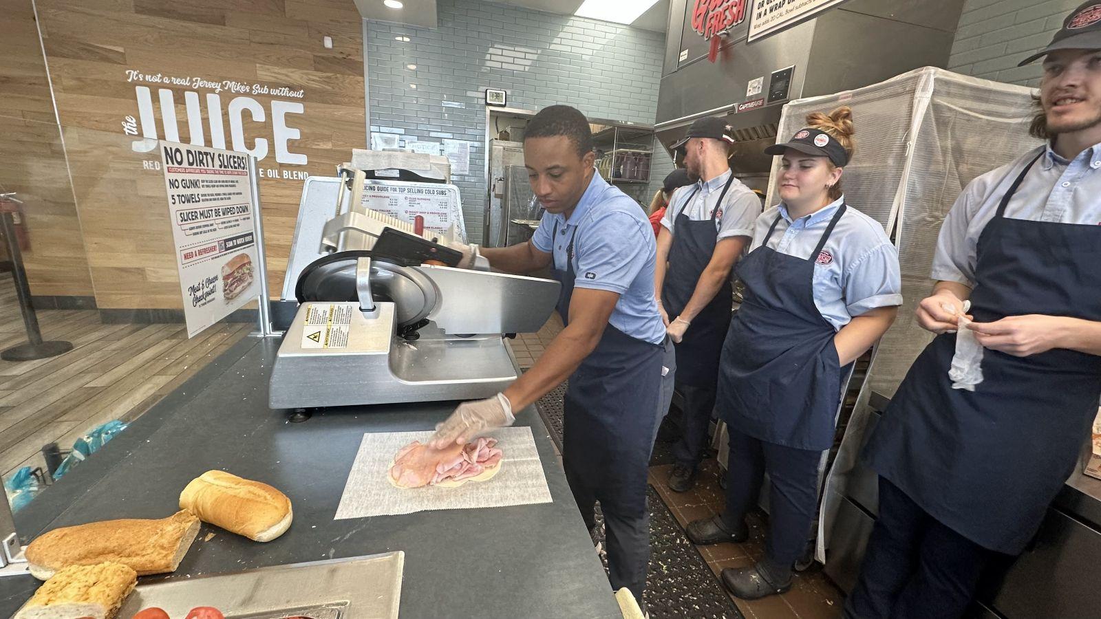 Mookie Golden making a sandwich while other workers look on