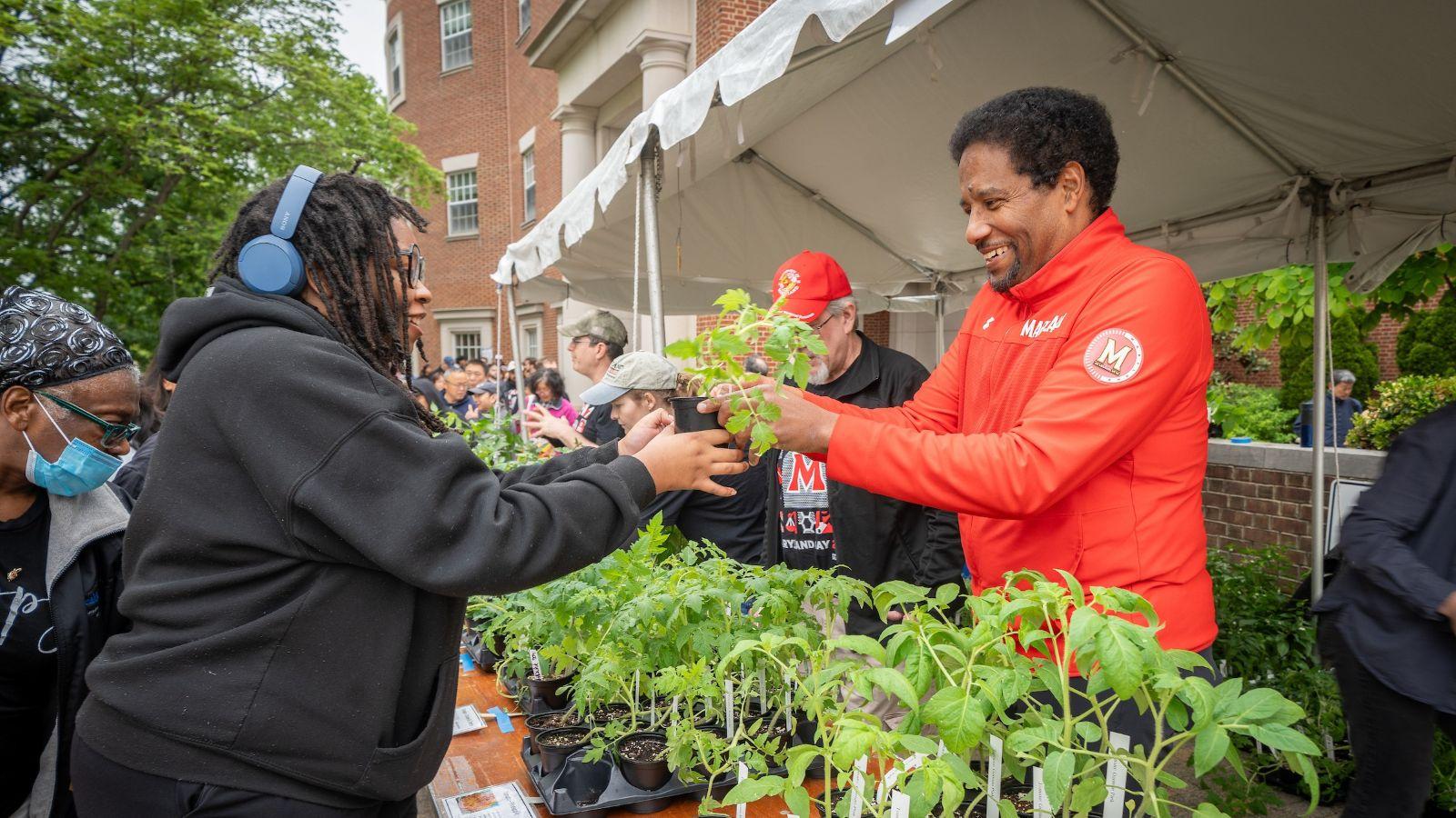 President Pines handing a plant to an attendee at Maryland Day