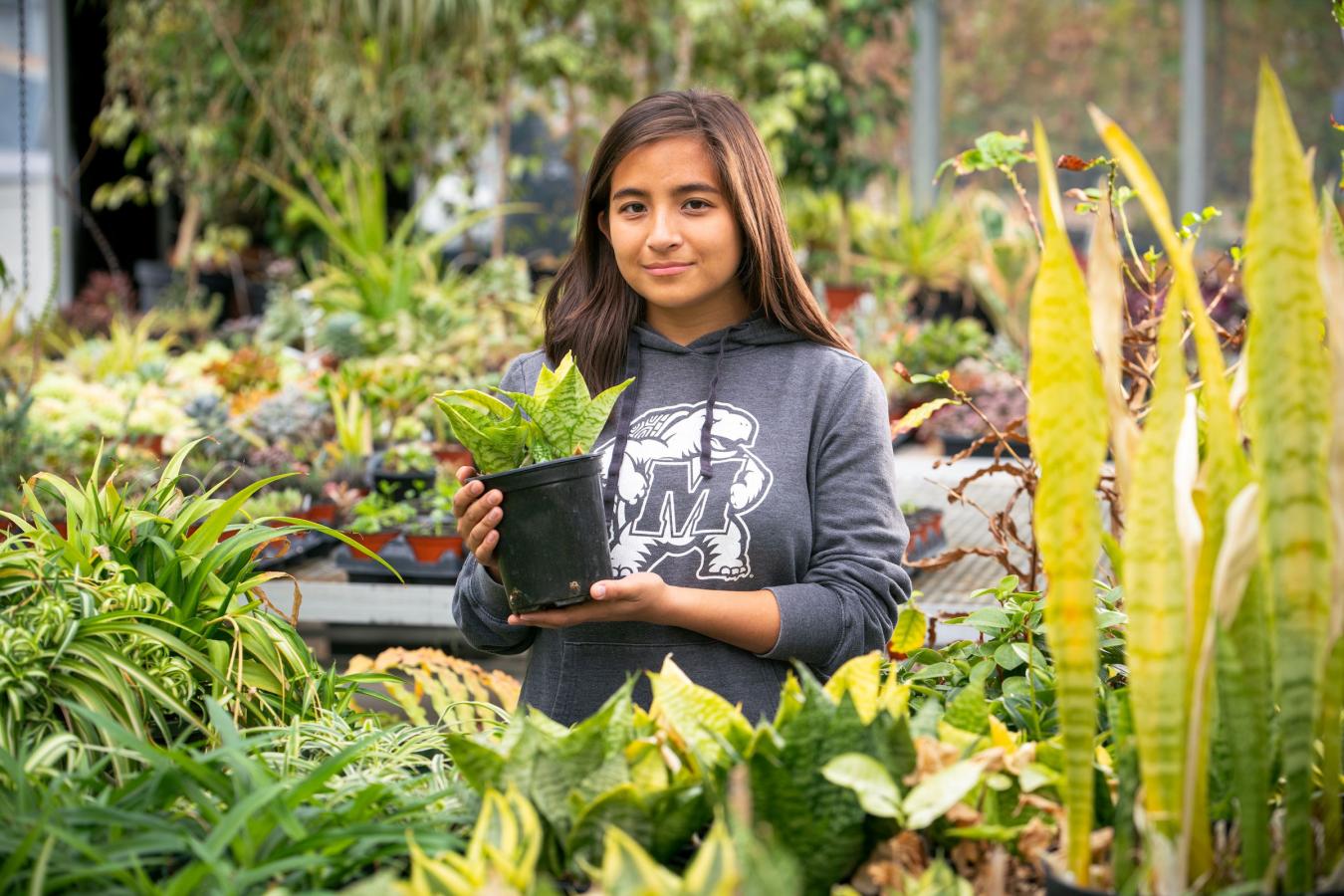 Student holding a plant at the Research Greenhouse