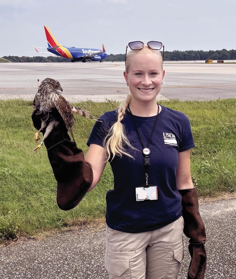 Hanna Weikert  holding a hawk in front of an airport