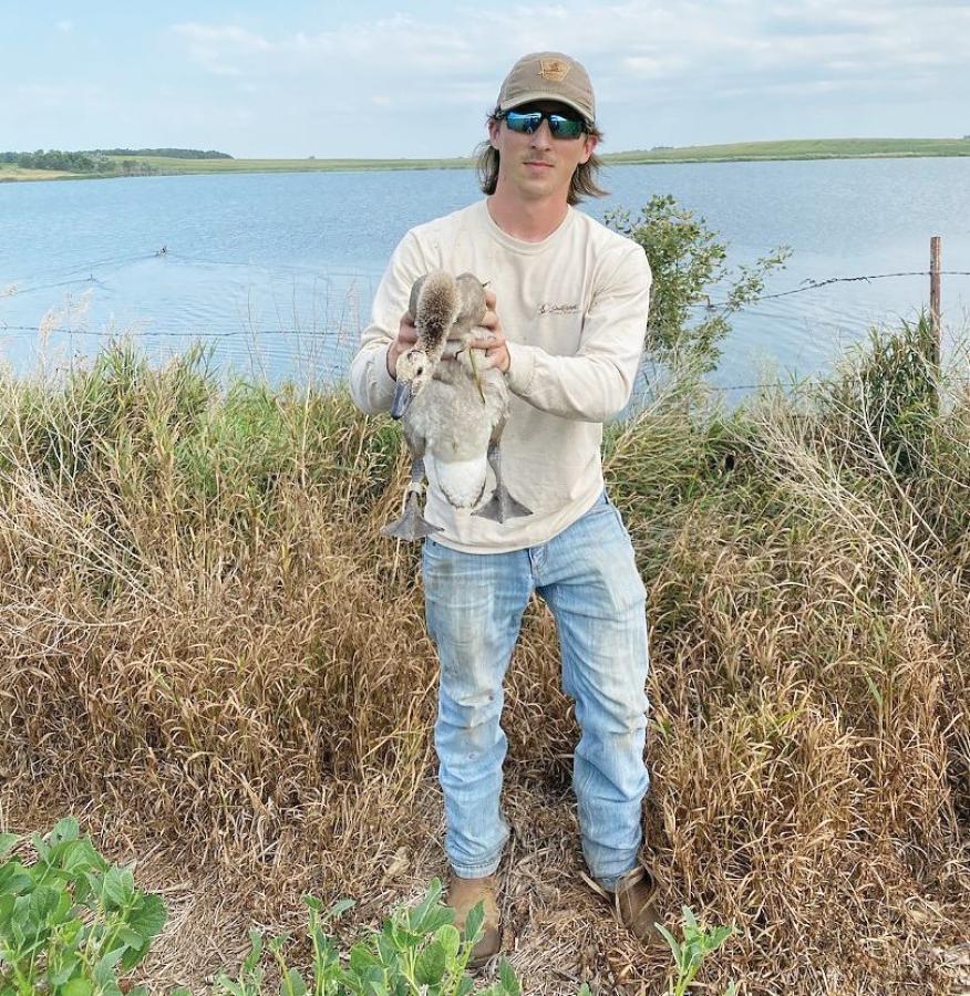 Dominic Patsy holding a bird near the water