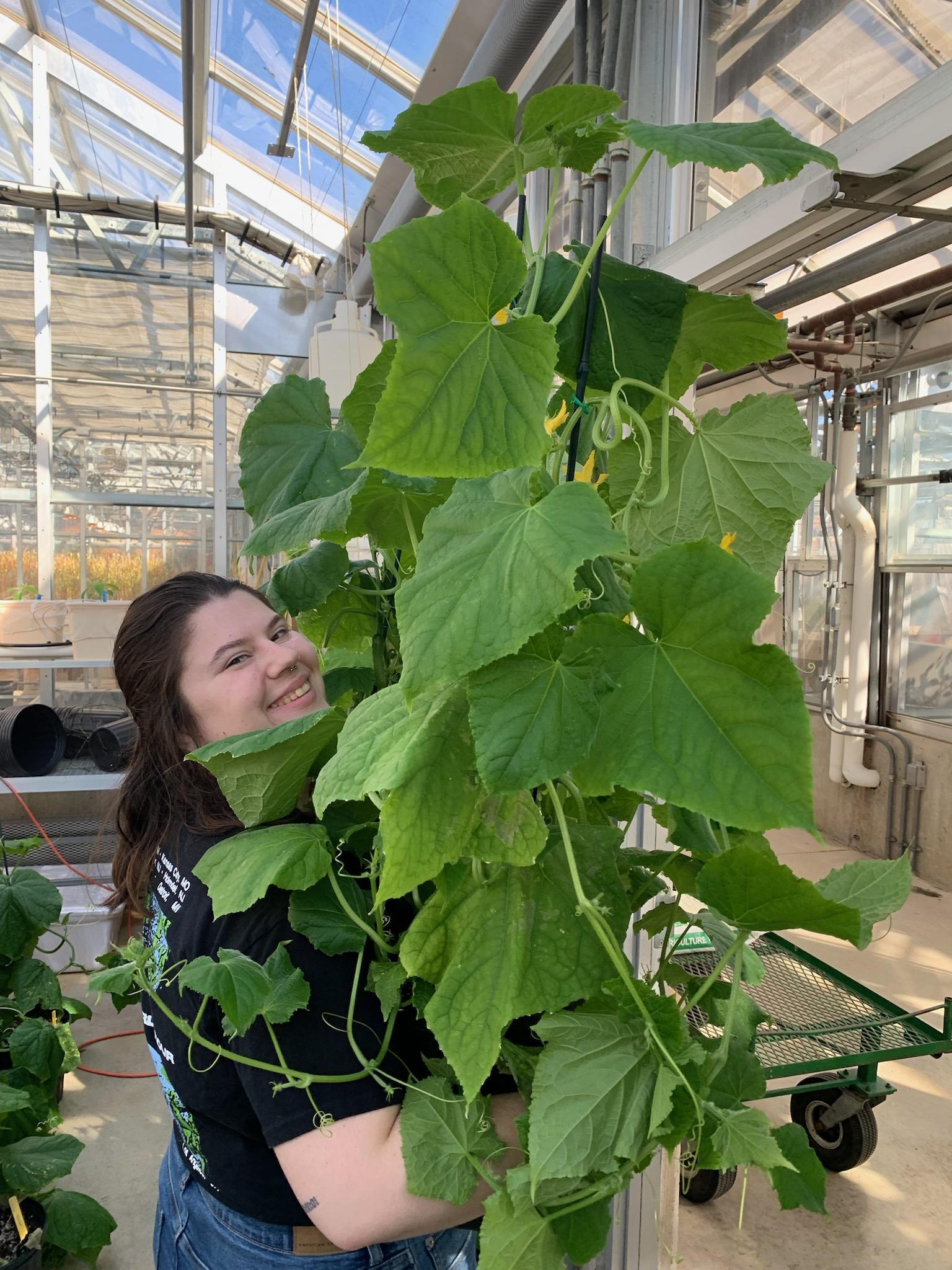 Sophie McCloskey. A happy student surrounded by plants!
